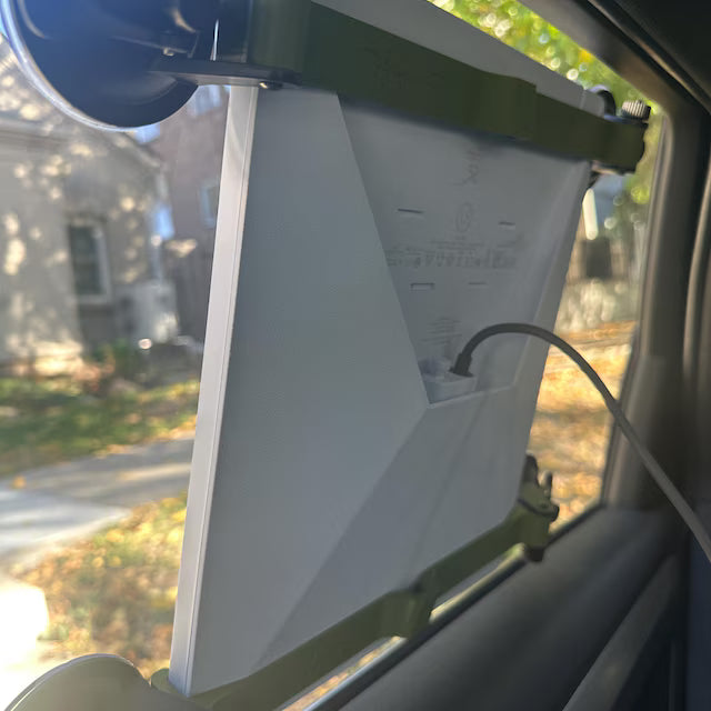 Starlink Mini suction cup mount on the inside of a car side window, green brackets and the dish's power cable attached